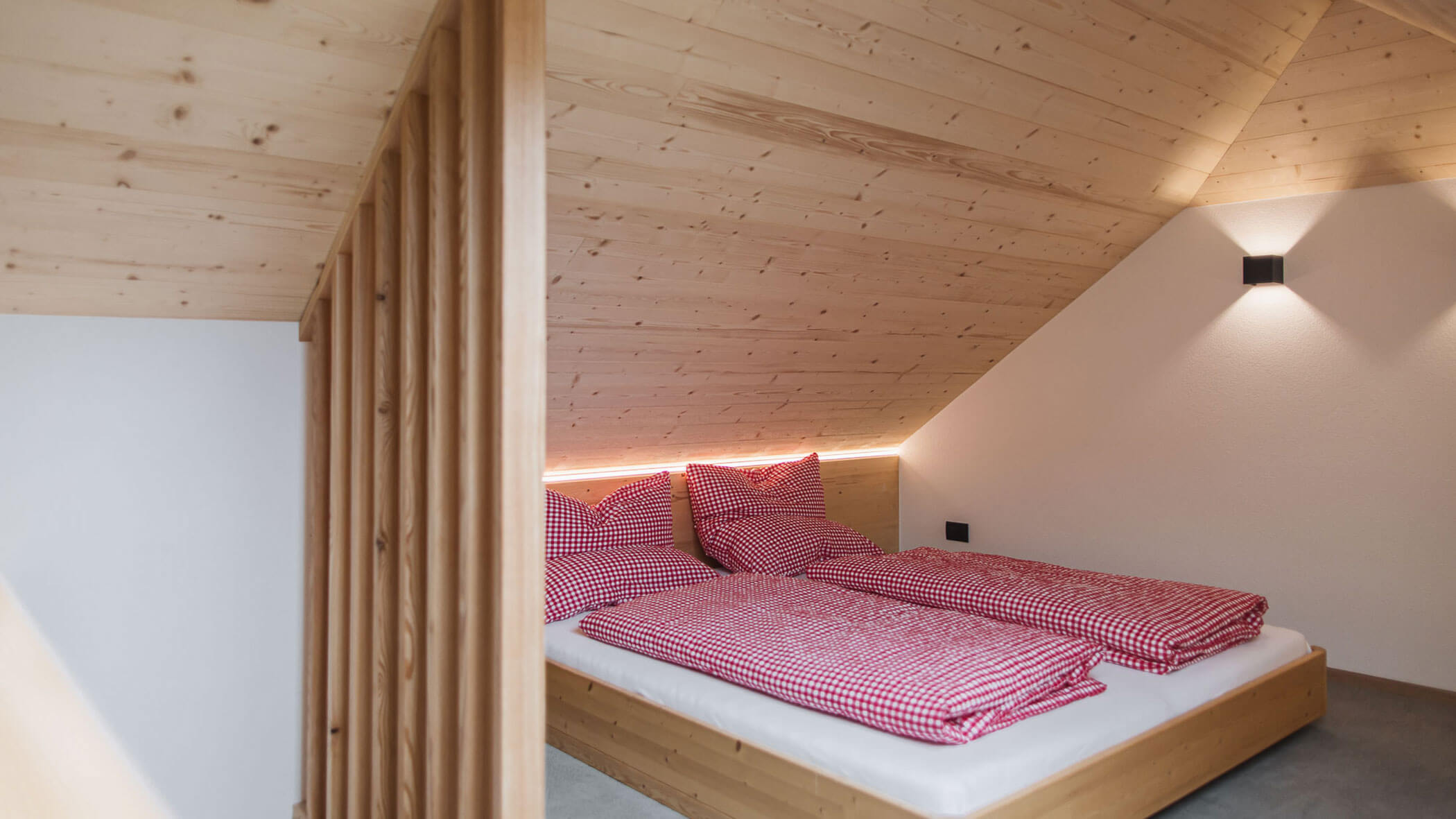 Holiday apartment - bedroom with red comforter - Obermairhof in Valdaora